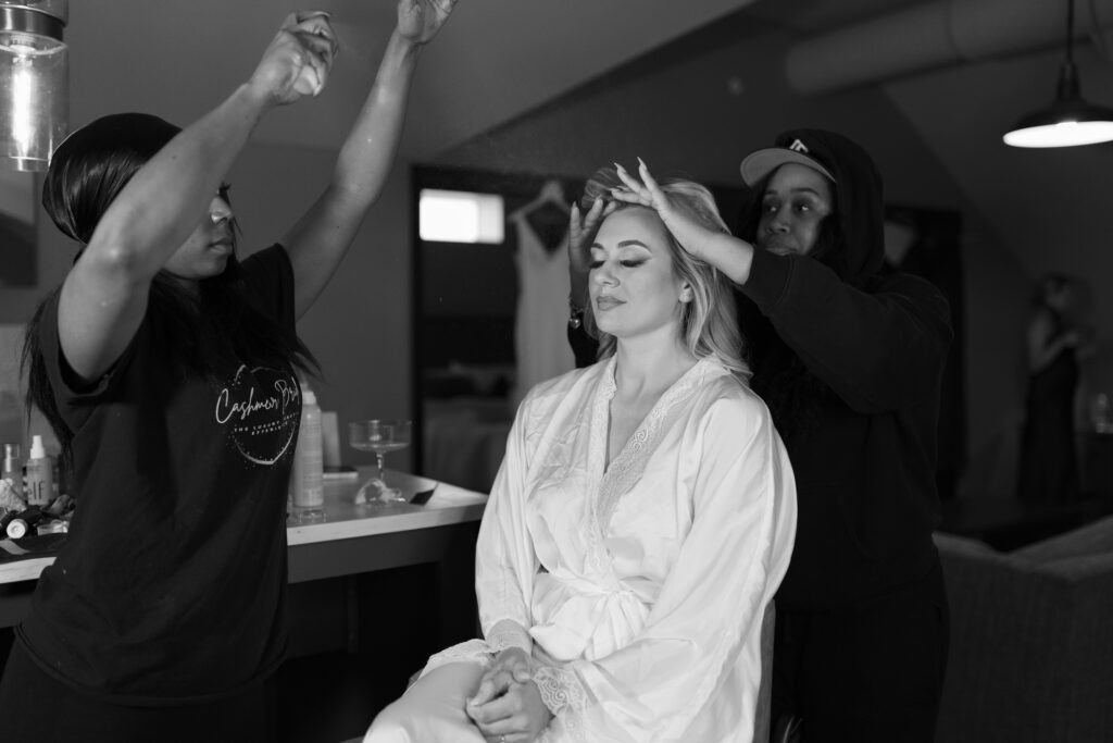 makeup artists applying finishing spray to brides face