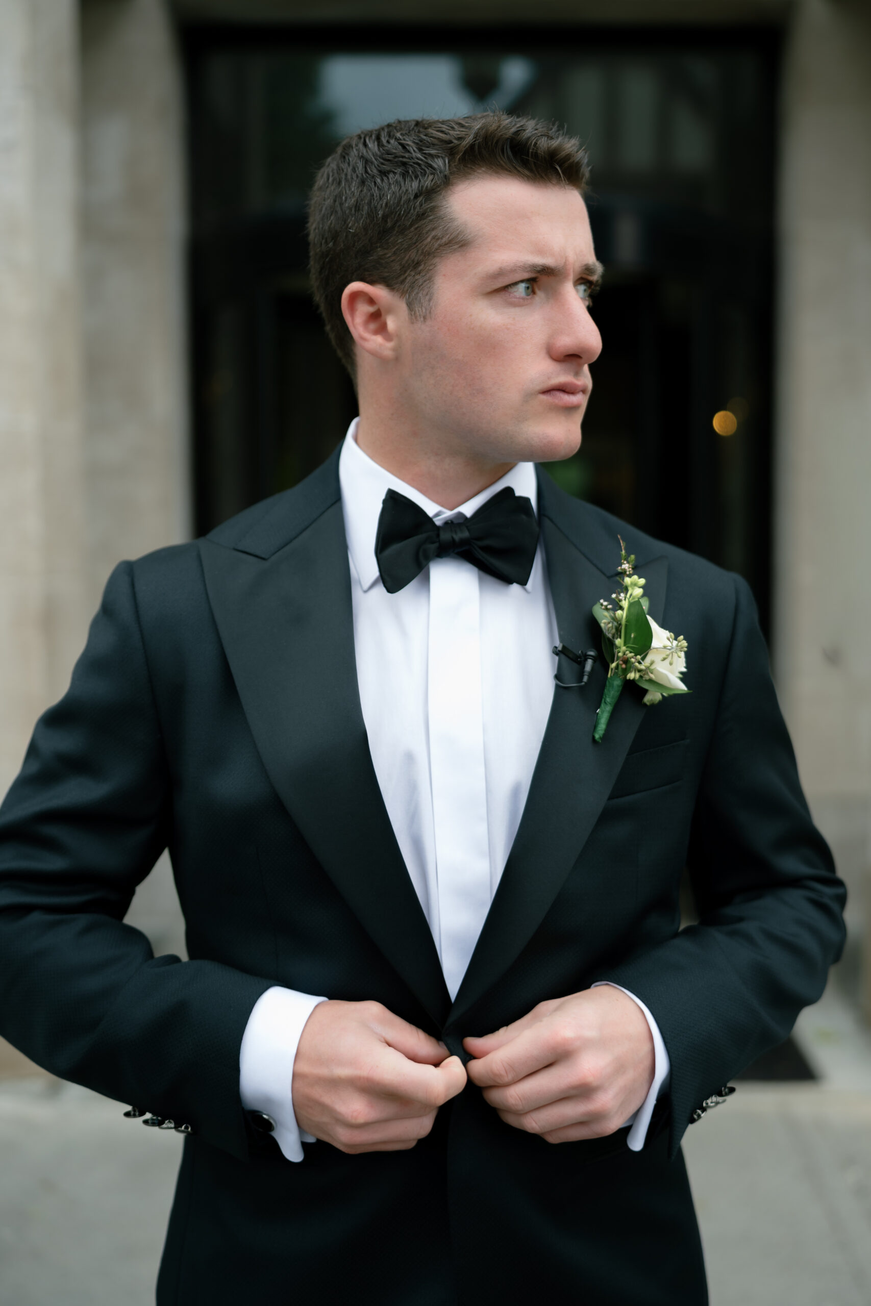 groom buttoning his jacket and looking out before the first look