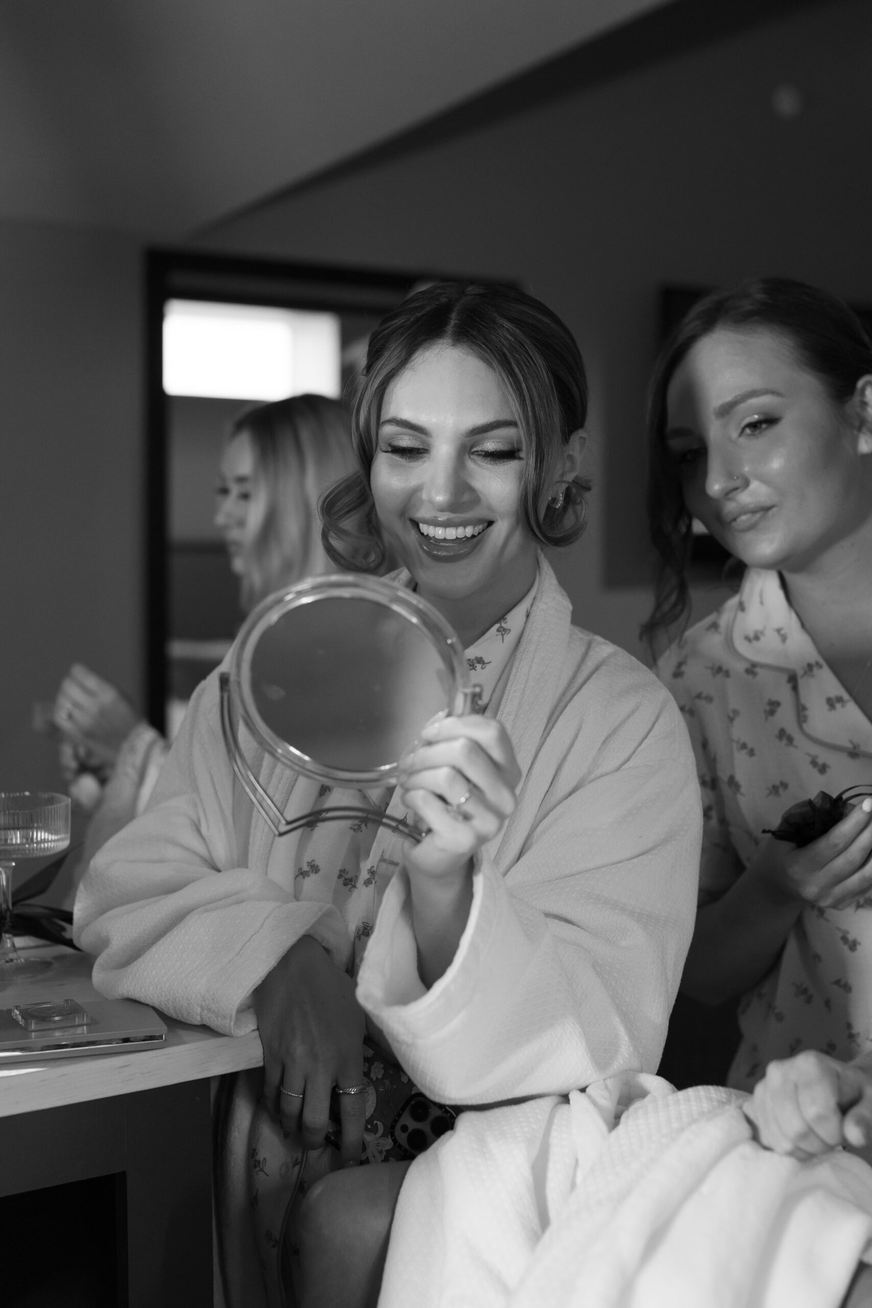 bridesmaids looking at their makeup in a hand held mirror