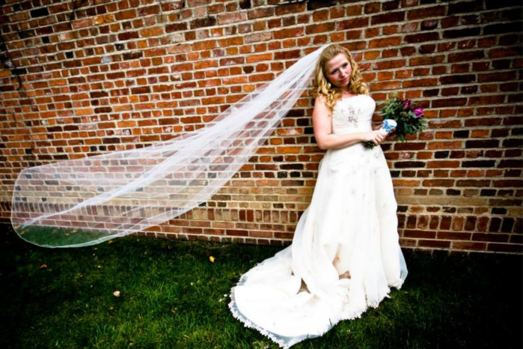 bride with veil against brick wall