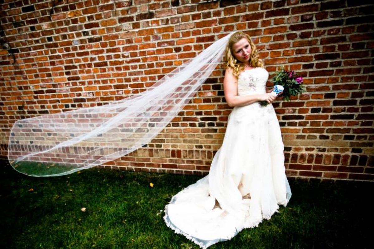 bride with veil against brick wall